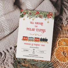 an orange slice is next to a christmas themed party card on a blanket with the words, all aboard the polar express