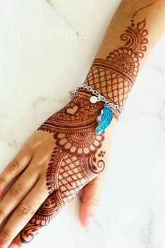 a woman's hand with henna on it and a blue beaded bracelet