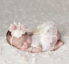 a baby is laying down wearing a white dress