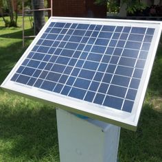 a solar panel on top of a white box in the grass