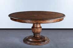 a round wooden table sitting on top of a gray floor