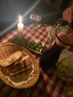 a table with bread, olives and wine on it next to a lit candle