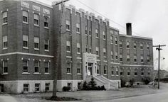 black and white photograph of an old brick building with stairs leading up to the second story