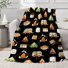 a black blanket with campers and cats on it in front of a white couch