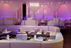 an empty restaurant with white booths and purple lighting