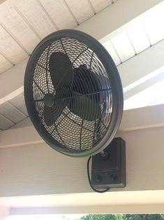 a black fan mounted on the side of a house