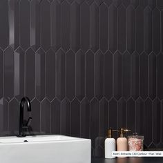 a white sink sitting next to a black tiled wall