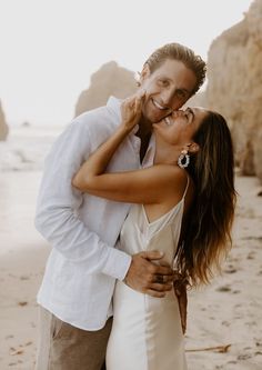 a man and woman kissing on the beach