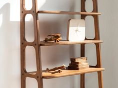 a wooden shelf with various items on it next to a white wall and a clock