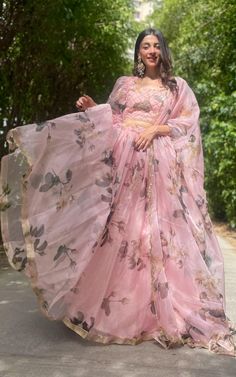 a woman in a pink dress is standing on the street with her arms spread out