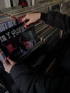 a person holding up a cd in front of a rack of cds on the floor