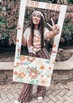 a woman is posing with her peace sign in front of some trees and flowers on the ground