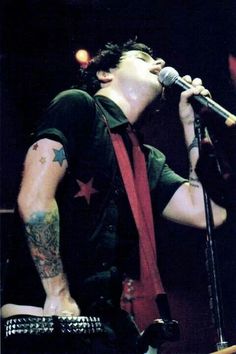 a man with tattoos on his arms and neck singing into a microphone at a concert