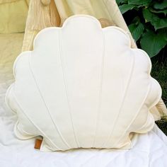 a white shell shaped pillow sitting on top of a bed