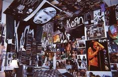 a room filled with lots of posters and pictures on the wall next to a lamp