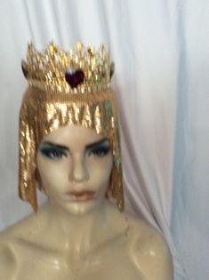 Gold metal crown, with ruby crystal hearts, on a gold metal mesh. INside a buckram base holds an adjustable strap for a good fit, one size fits all. Gold Crown Design Headpiece With Pinched Crown, Gold Regal Headpiece With Tall Crown, Royal Gold Crown For Parties, Royal Gold Party Crown, Royal Gold Crown With Pinched Shape, Royal Gold Crown With Tall Shape, Royal Gold Tall Crown, Gold Round Crown Headpiece For Party, Gold Structured Crown Headpiece For Festival