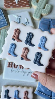 someone holding up some cookies decorated with cowboy boots and the words happy birthday on them