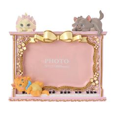 two cats are sitting on top of a pink photo frame with gold trimmings