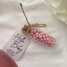 a small jar filled with pink and white candy next to a flower on a t - shirt