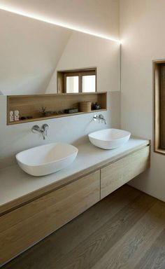 two white bowls sit on top of a counter in a room with wood flooring