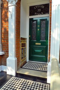 a green door is on the side of a brick building with black and white checkered flooring