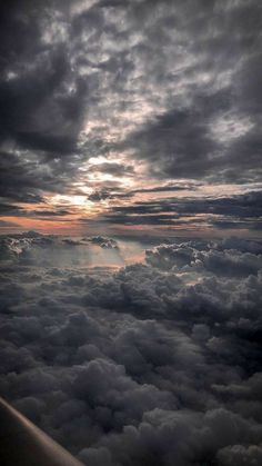 the view from an airplane looking down on clouds and sun rays in the sky above