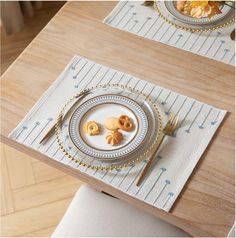 two plates with pastries on them sitting on a wooden table next to silverware