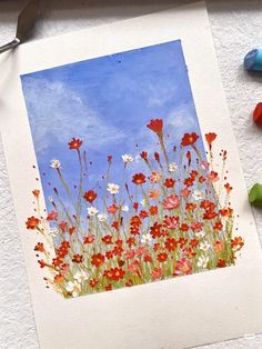 a painting of red, white and blue flowers with crayons next to it