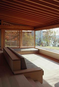 an empty room with wooden flooring and large windows looking out onto the water outside