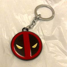 a deadpool keychain is shown on a white sheet with yellow light coming from its eyes