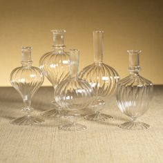 five clear glass vases sitting on top of a table next to eachother