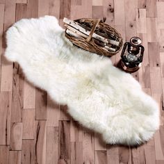 a white sheepskin rug on a wooden floor next to a basket and bottle opener