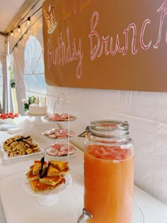 a table topped with lots of desserts and drinks next to a sign that says happy birthday brunch