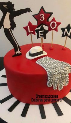 a red cake with black and white decorations on it's topper, including a cowboy hat