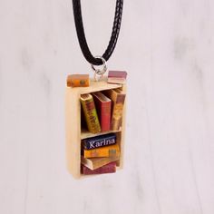 a wooden box with books in it hanging from a leather cord