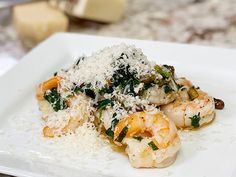 a white plate topped with pasta and shrimp covered in parmesan sprinkles