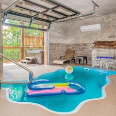 an indoor swimming pool with inflatable toys floating on the water and sliding glass doors