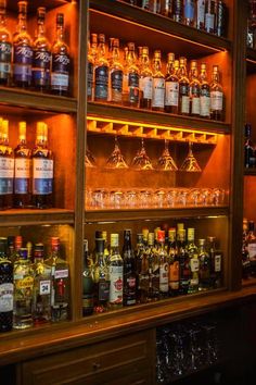 many bottles and glasses are lined up on the shelves