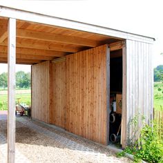 an open wooden garage door on the side of a building with grass and trees in the background