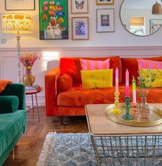 a living room filled with colorful furniture and pictures on the wall above it's coffee table