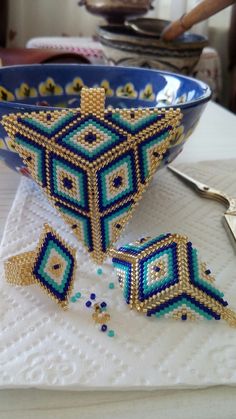 a blue bowl sitting on top of a table next to two pieces of beaded jewelry