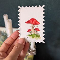 a hand holding a stamp with a mushroom on it