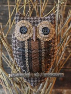 an owl ornament hanging from a twig on a branch with twigs in the background