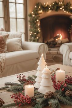 a living room decorated for christmas with candles and pine cones on the coffee table in front of the fireplace