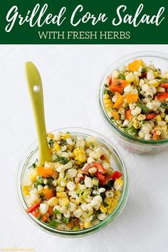 two glass bowls filled with corn salad on top of a white table cloth next to a green plastic spoon