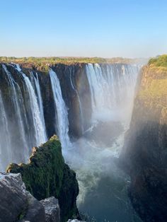 iguana falls in the background with water pouring from it's sides and trees on either side