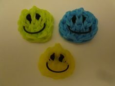 three different colored hair clips with faces drawn on them and one has a smiley face