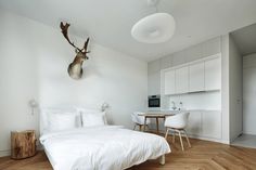 a white bed sitting in a bedroom next to a wooden table and chair on top of a hard wood floor