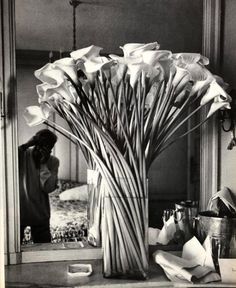 a vase filled with white flowers sitting on top of a counter next to a mirror