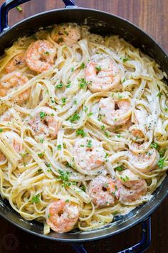 pasta with shrimp and parsley in a skillet on a wooden counter top, ready to be eaten